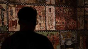 Visitor viewing a wall of ancient Jewish artwork and illustrations at ANU – Museum of the Jewish People in Tel Aviv.